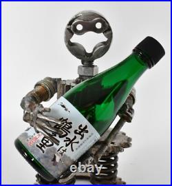 Homme tenant une bouteille sculptures faites de pièces de moto fabriquées à l
