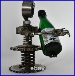Homme tenant une bouteille sculptures faites de pièces de moto fabriquées à l