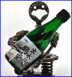 Homme tenant une bouteille sculptures faites de pièces de moto fabriquées à l