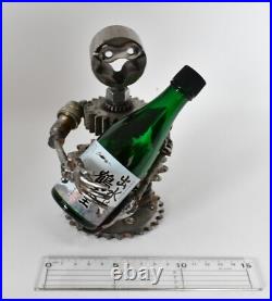 Homme tenant une bouteille sculptures faites de pièces de moto fabriquées à l