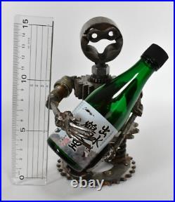 Homme tenant une bouteille sculptures faites de pièces de moto fabriquées à l
